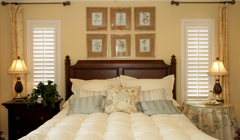 Tall plantation shutters framing bed in a bedroom in Denver 